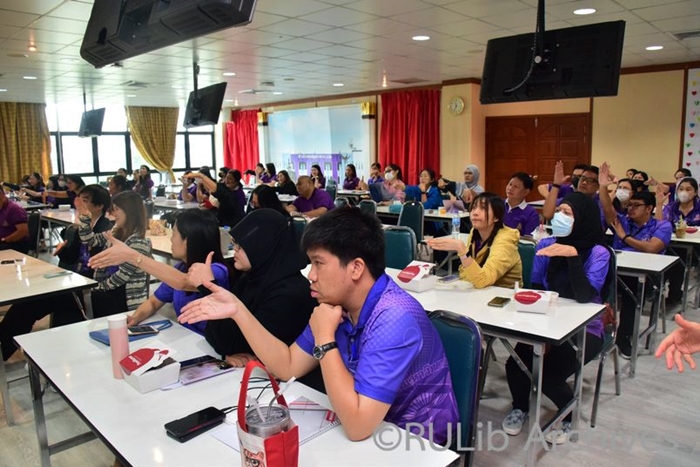 ภาพบุคลากรสำนักหอสมุดกลาง มหาวิทยาลัยรามคำแหงฝึกท่าจับถังดับเพลิงขณะใช้ดับไฟ