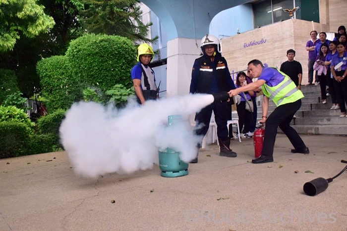 ภาพอาจารย์ ดร.ภูวเดช ธนิชานนท์ ผู้อำนวยการสำนักหอสมุดกลาง ดับเพลิงโดยใช้ถังดับเพลิง เพื่อดับไฟจากถังแก๊ส
