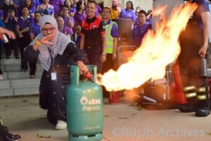 ภาพนางสาวฟาฎีล่า สนูวงศ์ ตัวแทนฝ่ายบริการสารสนเทศ ฝึกปิดถังแก๊สขณะเกิดเพลิงลุกไหม้
