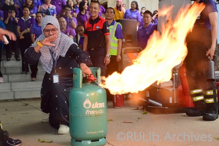 ภาพนางสาวฟาฎีล่า สนูวงศ์ ตัวแทนฝ่ายบริการสารสนเทศ ฝึกปิดถังแก๊สขณะเกิดเพลิงลุกไหม้